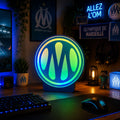 Lampe LED RGB OM Ultimate de LampeGeek avec lumière colorée et design moderne, allumée sur fond neutre.